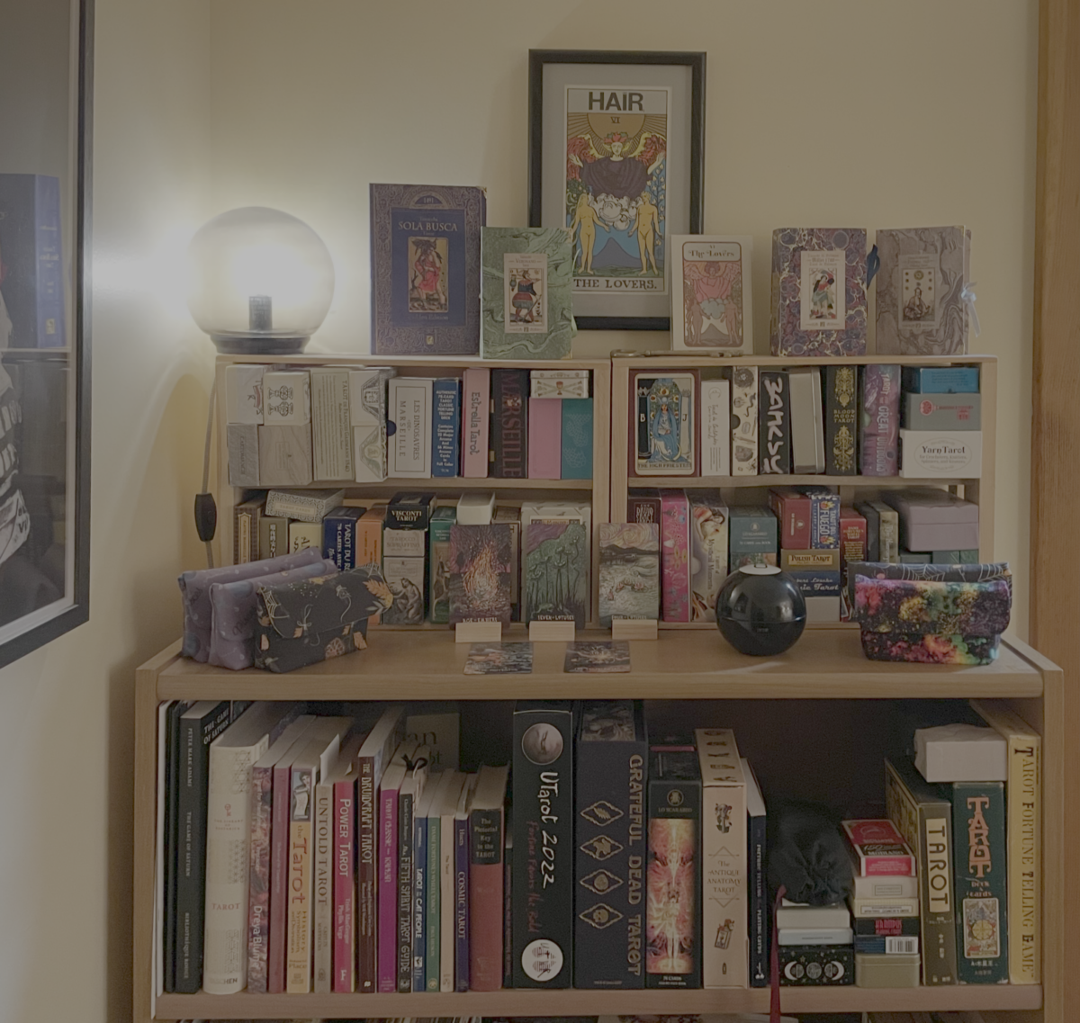 Many tarot decks organized in tiers on a bookshelf