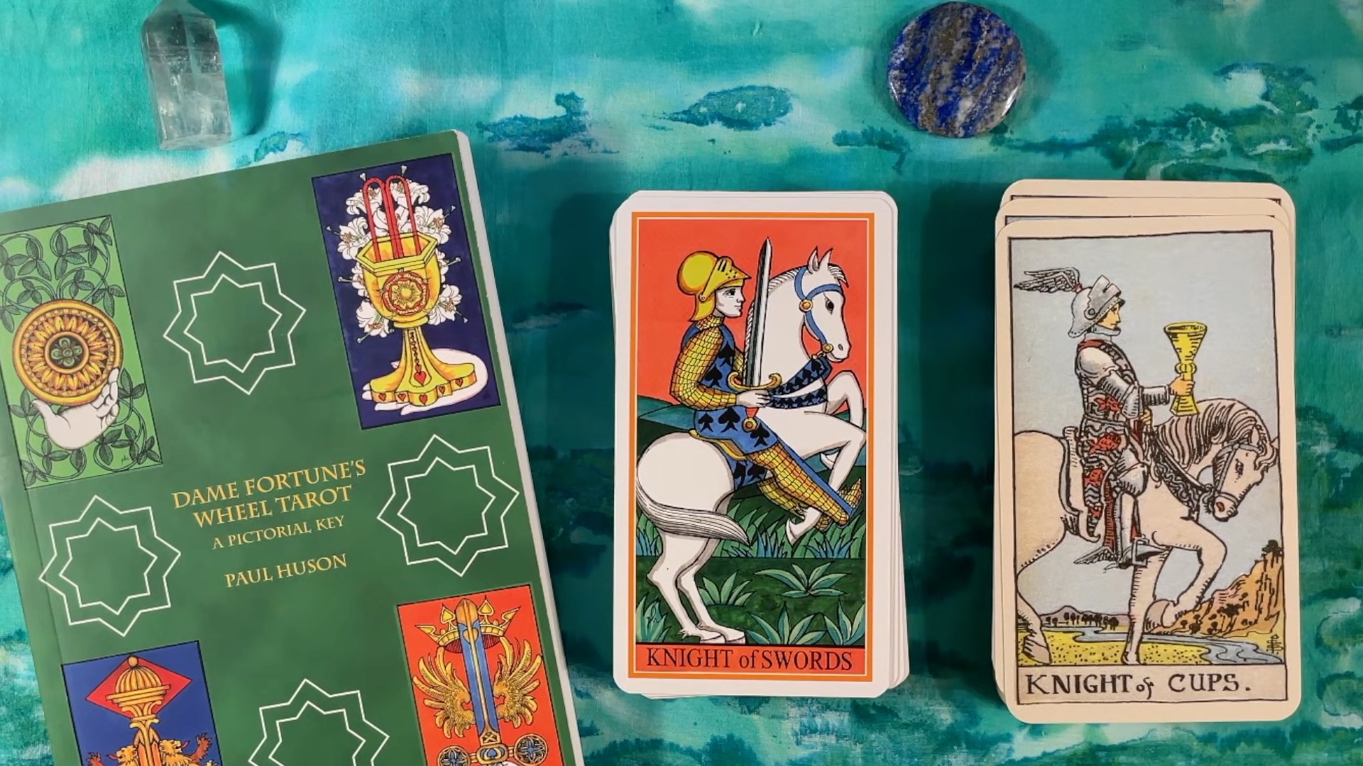 The Dame Fortune's Wheel guidebook and a card from the pack, next to a card from the Waite-Smith tarot.