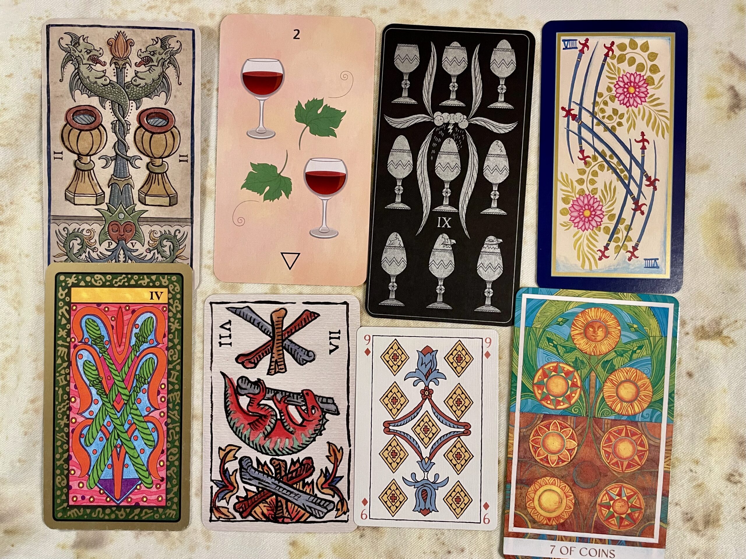 Eight pip cards from different decks showing a variety of art styles, colors, complexity and arrangements.