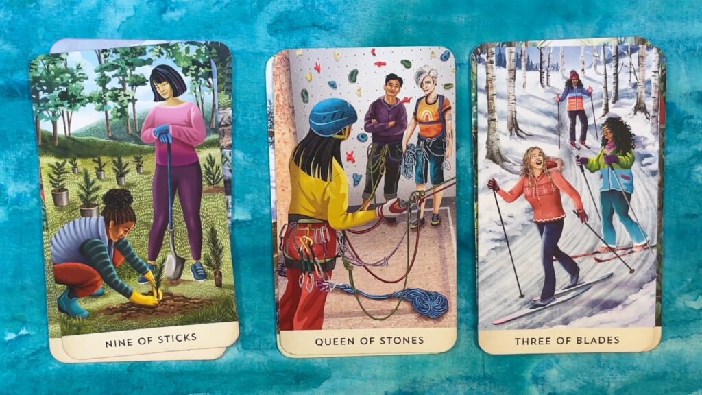 Three cards from the Tarot for the Great Outdoors, featuring images of seemingly same-gendered people enjoying activities such as rock climbing and skiing.
